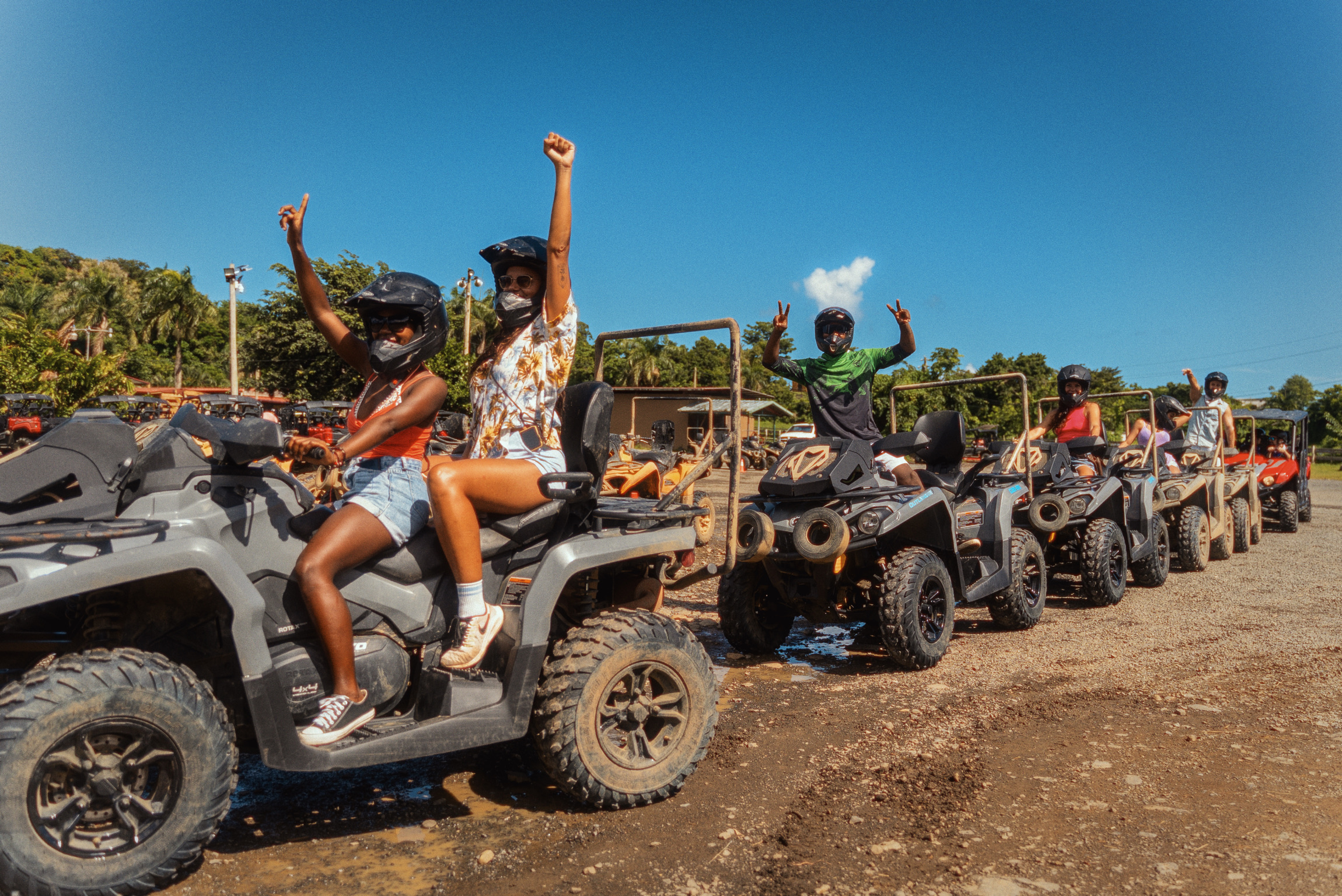 Group riding ATVs on a sunny day with helmets and masks.