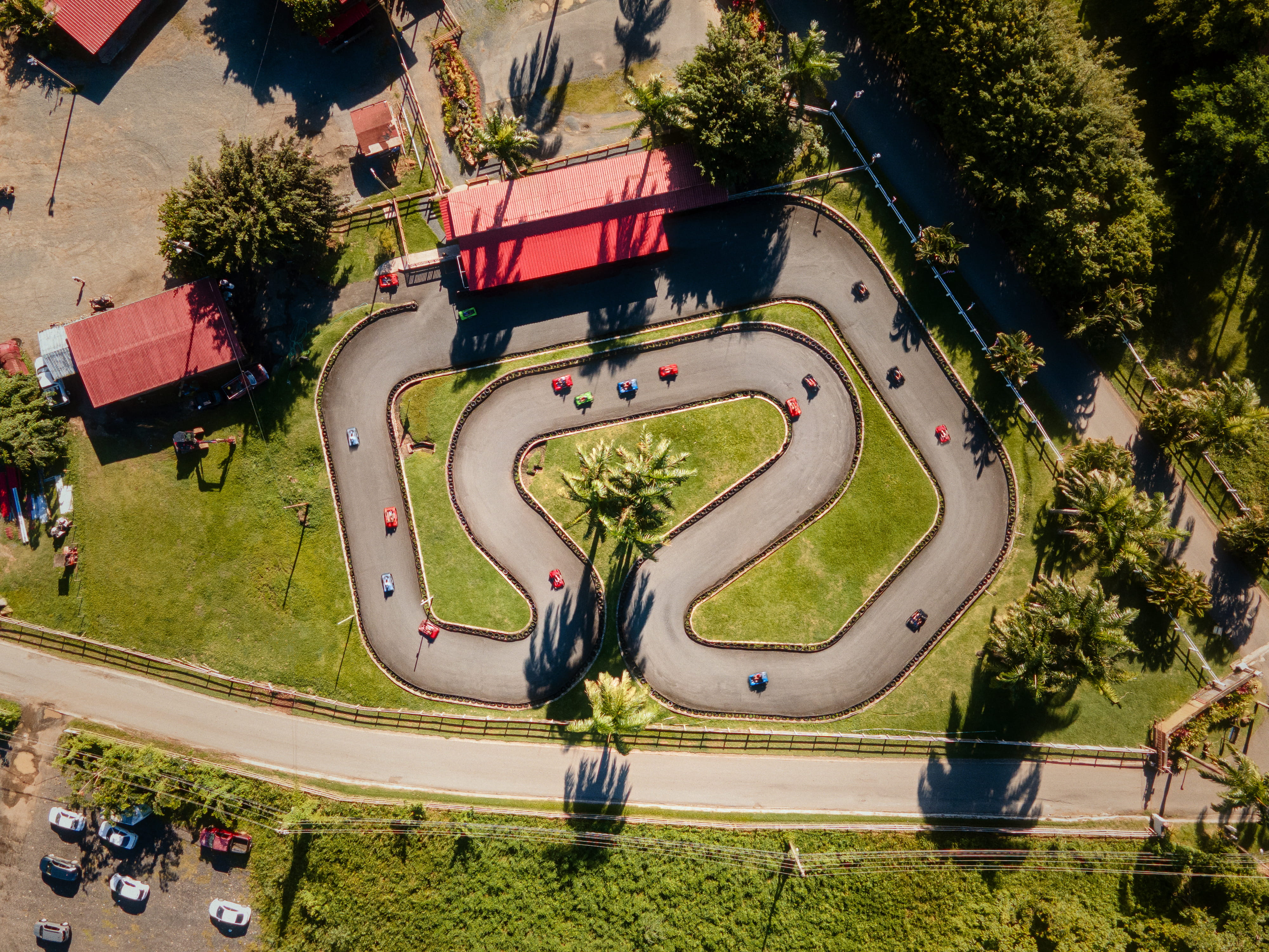 Aerial view of go-kart track with karts and nearby trees.