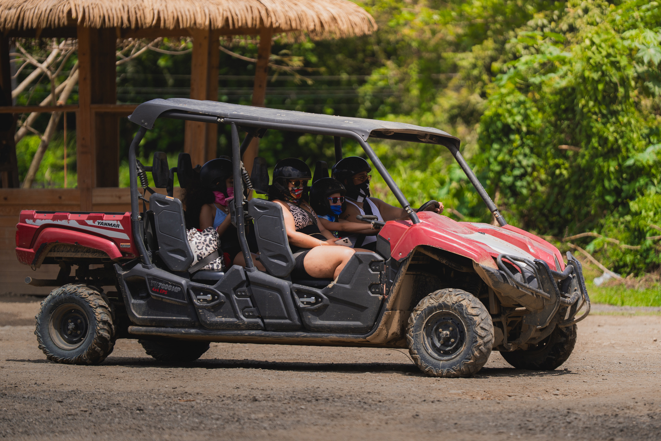 Four people riding a red all-terrain vehicle on a dirt path.