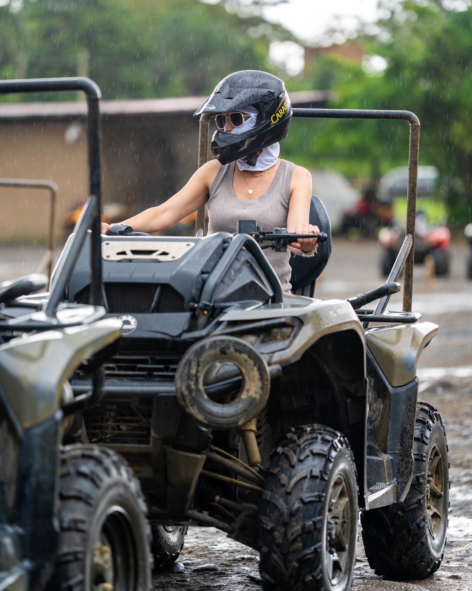 Person wearing helmet driving an ATV in a muddy area.