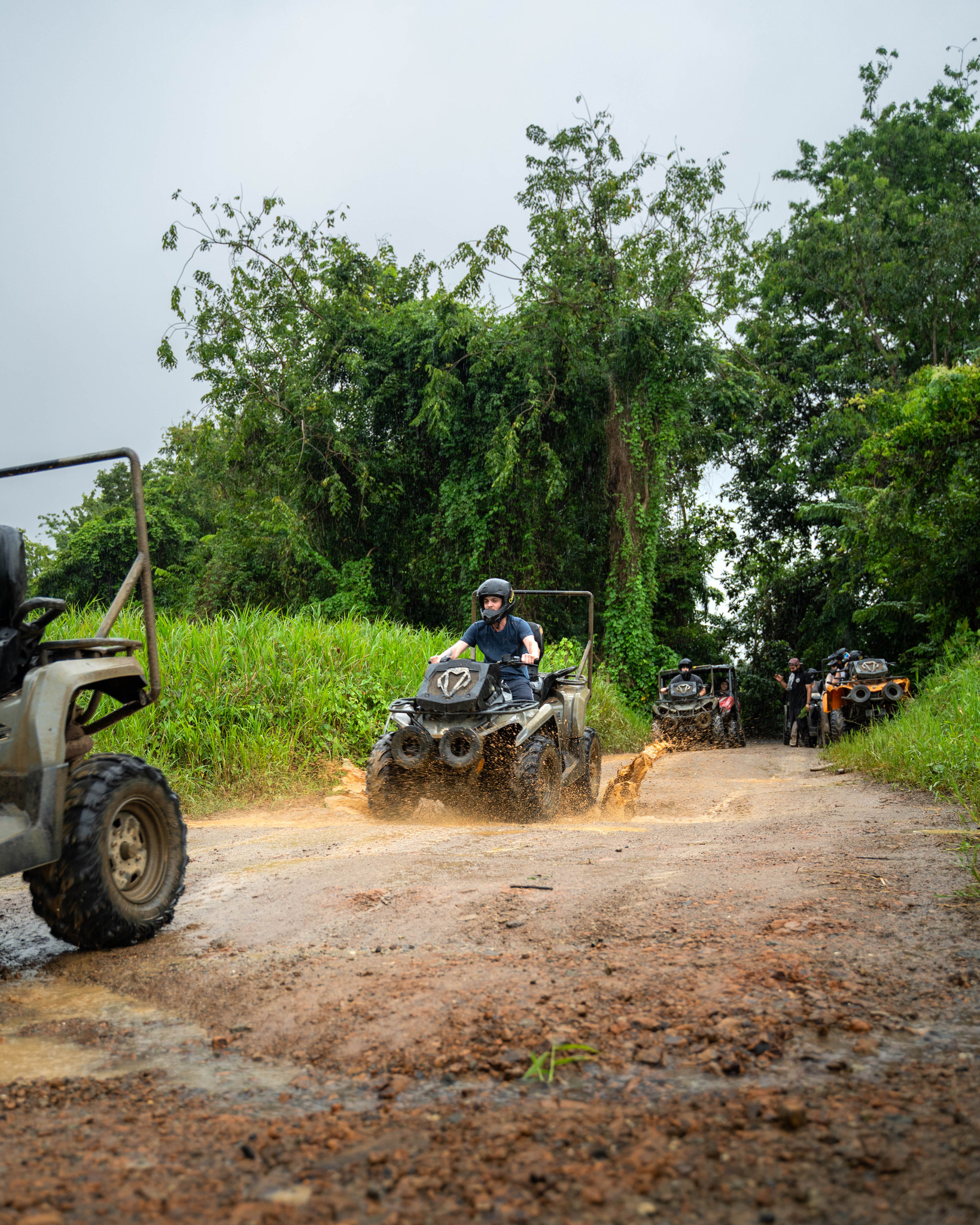 People riding ATVs on a muddy forest trail