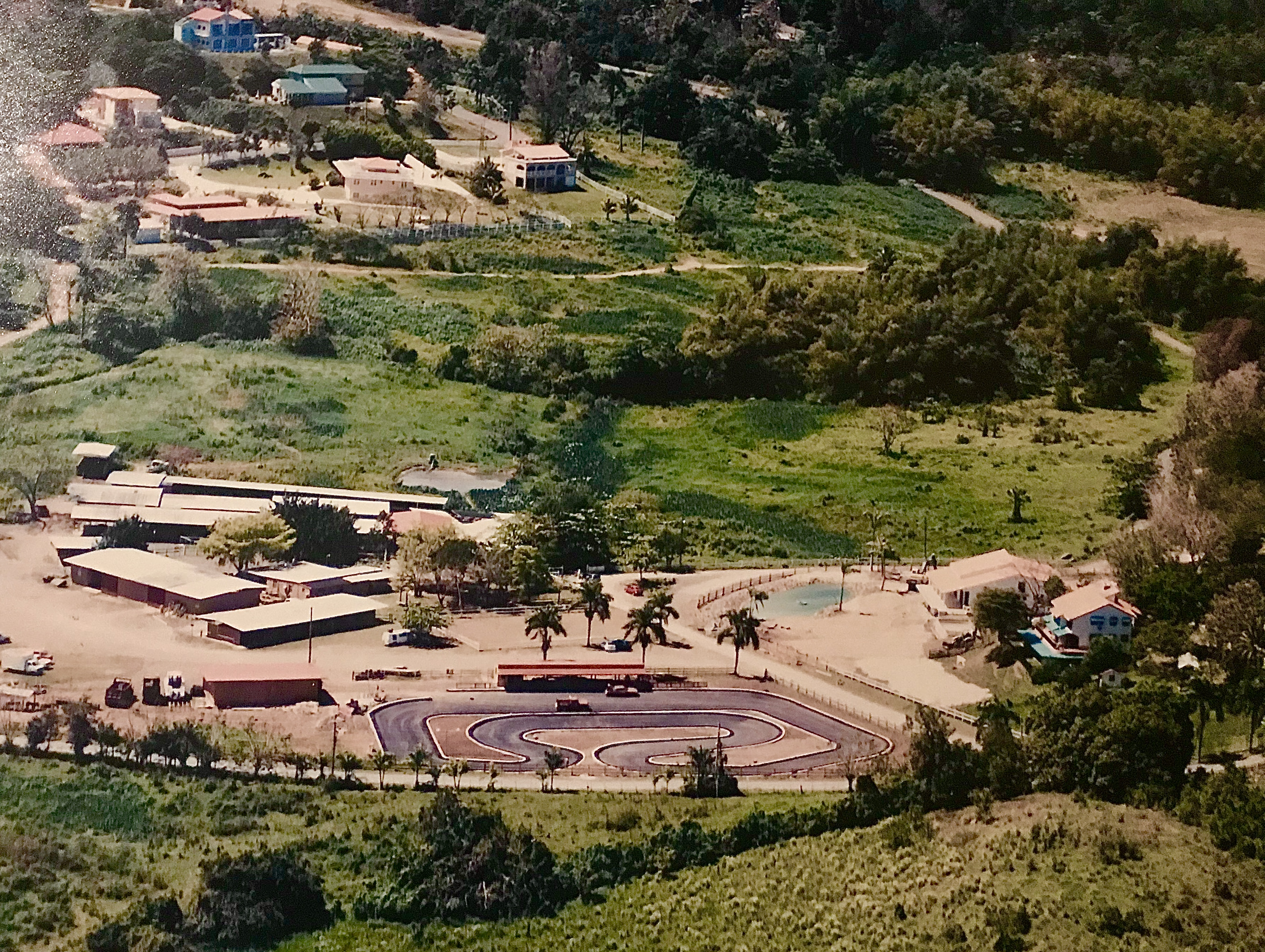 Aerial view of a rural landscape with a track, fields, and scattered buildings.