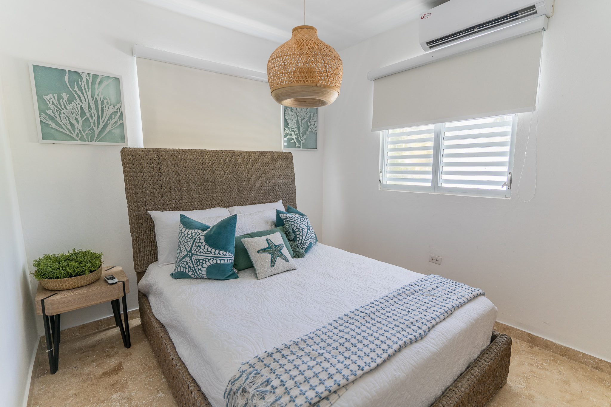 Cozy bedroom with a woven headboard, coastal decor, and a wicker pendant light.