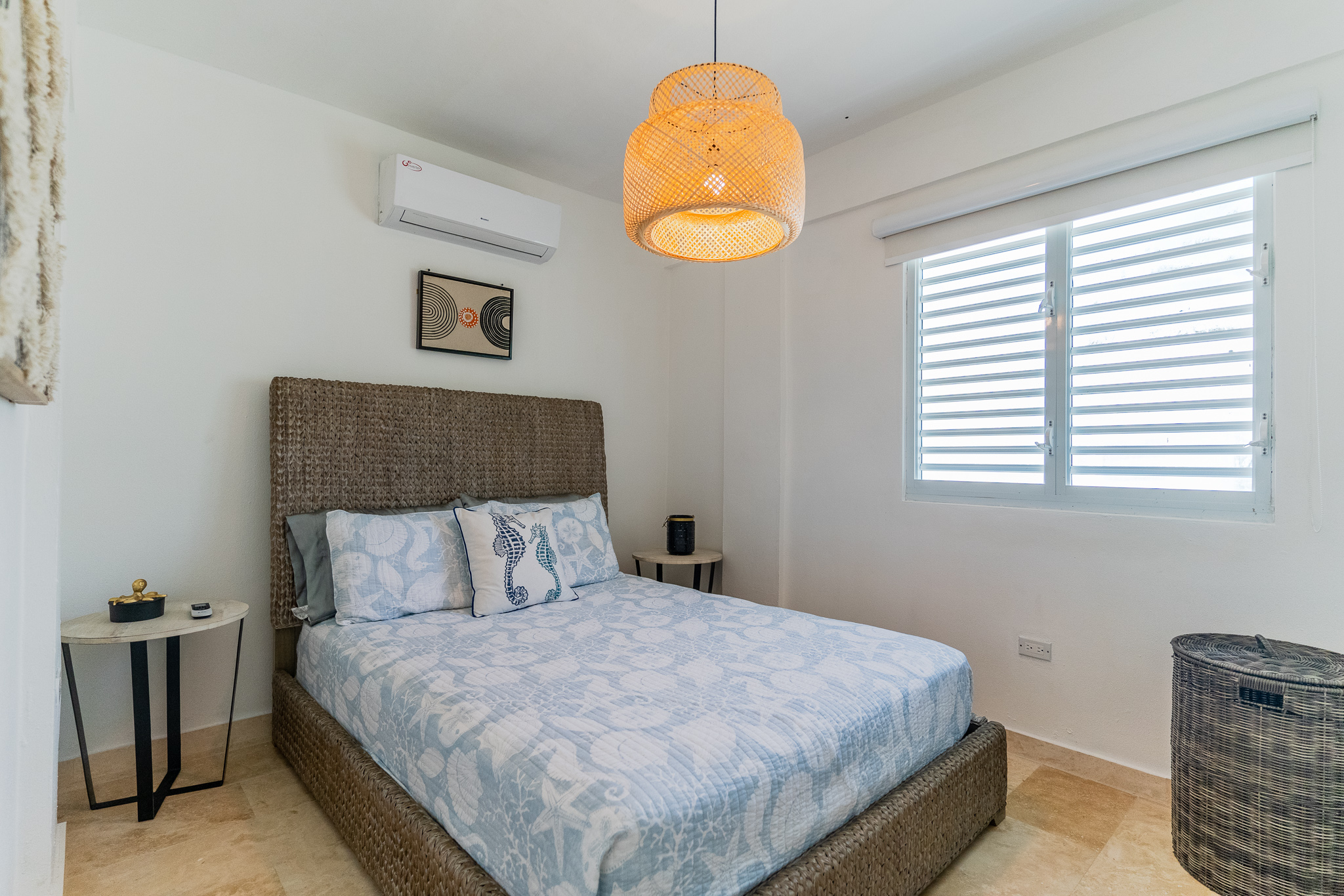 Cozy bedroom with wicker bed, bedside tables, and a woven pendant light.