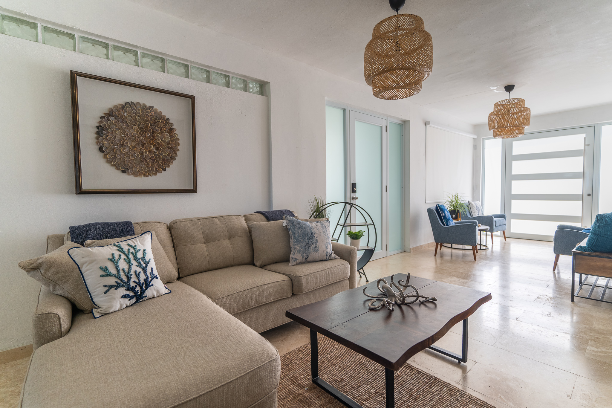Modern living room with beige sofa, wooden table, and wicker pendant lights.