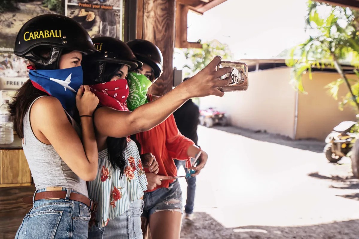 Tres personas con casco y pañuelo tomándose un selfie al aire libre.