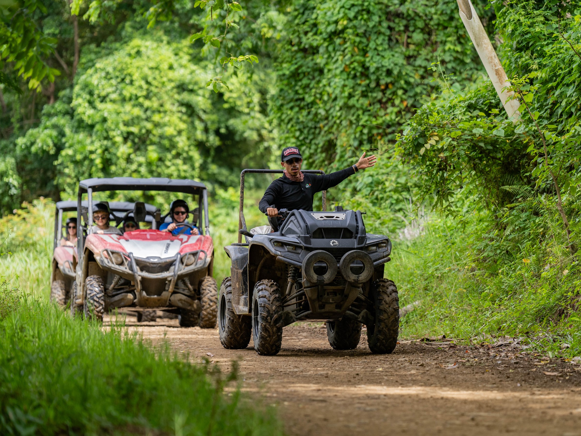 a person riding on the back of a truck driving down a dirt road