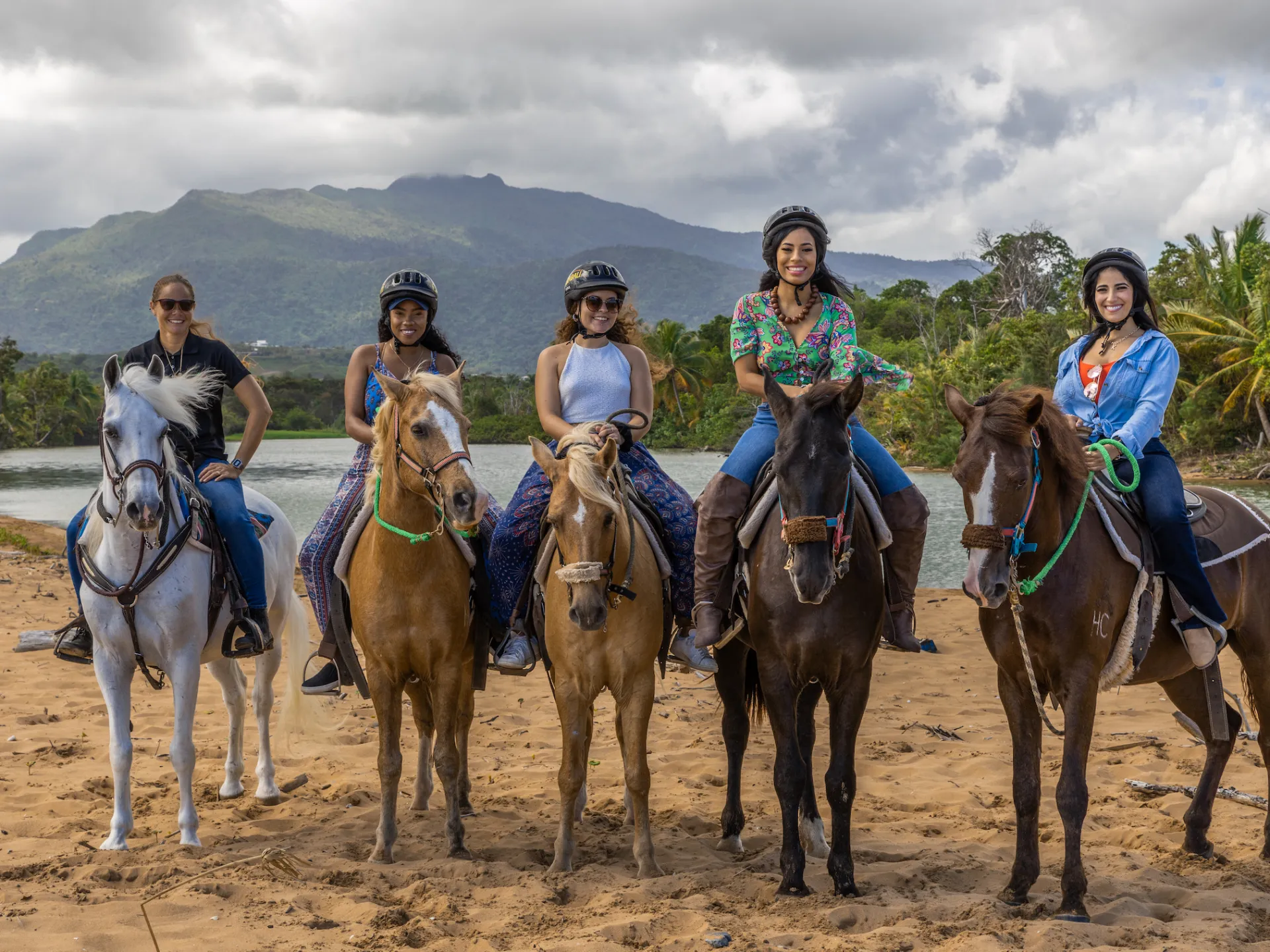 a group of people riding horses on a beach