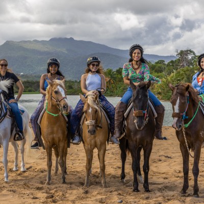 a group of people riding horses on a beach