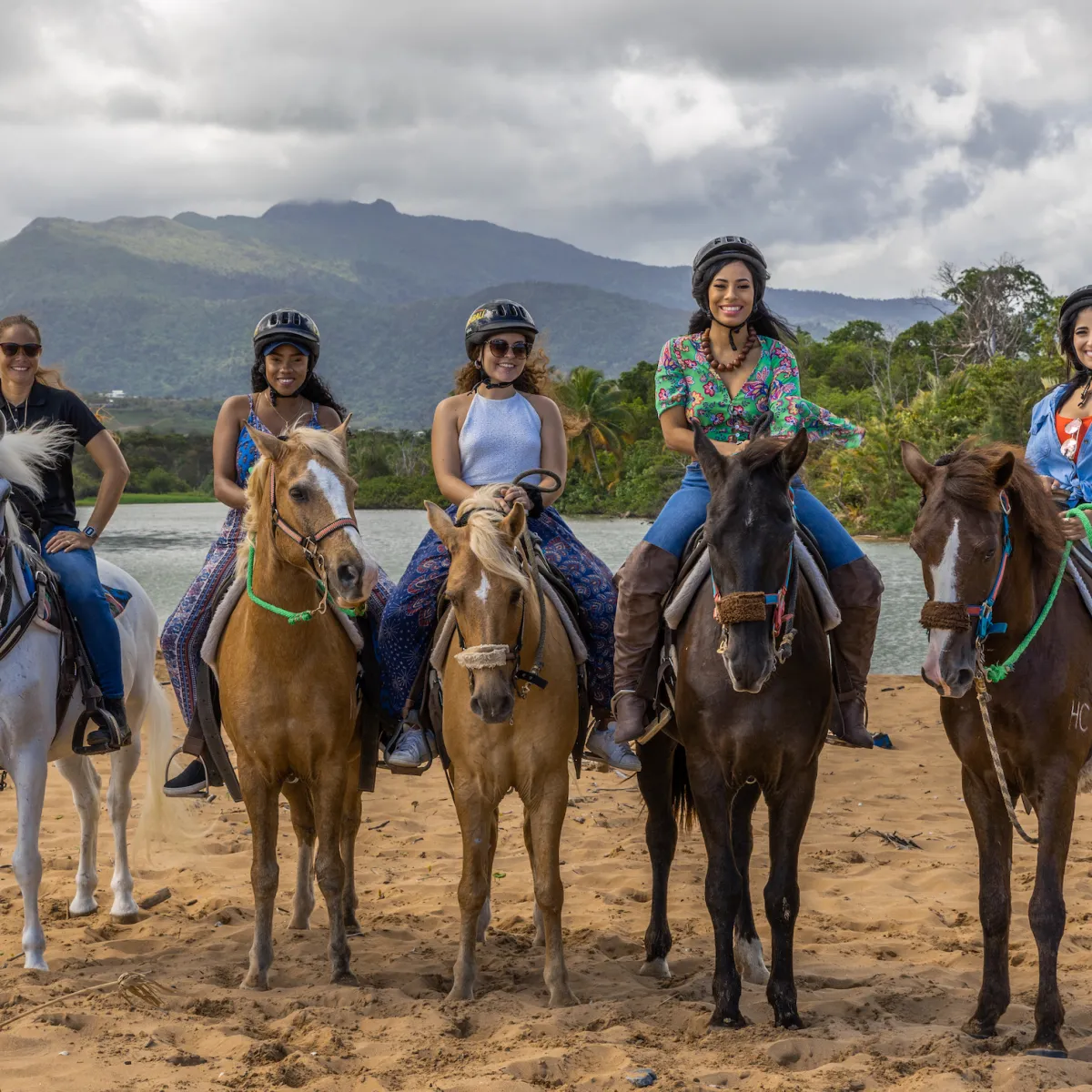 a group of people riding horses on a beach